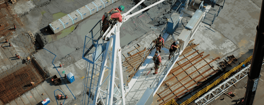 construction crane safety, construction workers standing on a crane while putting it together